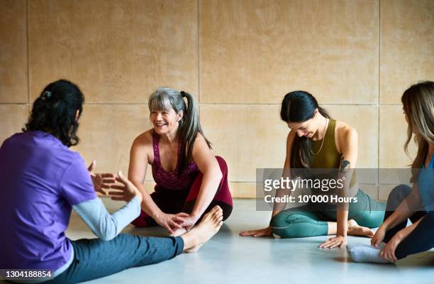small group in yoga studio talking and stretching - disrupt aging stock pictures, royalty-free photos & images