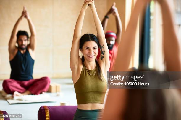 woman smiling with arms raised in yoga position - ein tag im leben stock-fotos und bilder