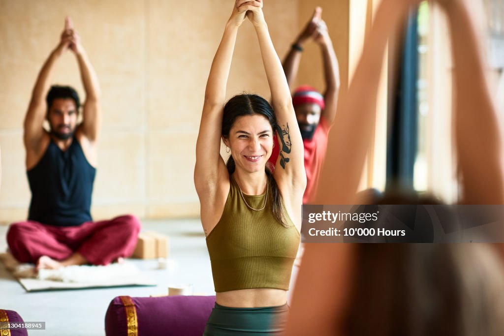 Woman smiling with arms raised in yoga position