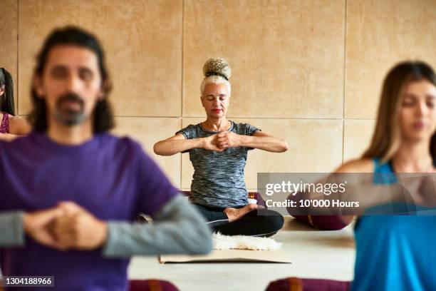 senior woman with hands clenched in yoga position - ein tag im leben stock-fotos und bilder