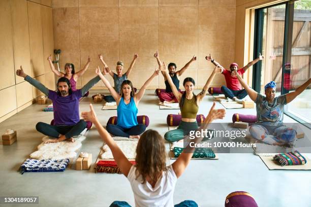 multi-ethnic group with arms raised in yoga studio - yoga stock-fotos und bilder