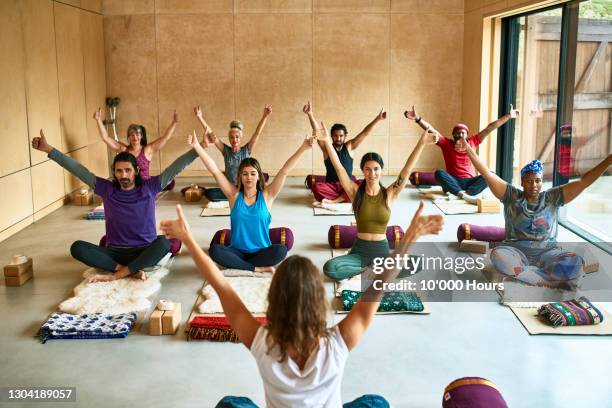 multi-ethnic group with arms raised in yoga studio - een dag uit het leven serie stockfoto's en -beelden