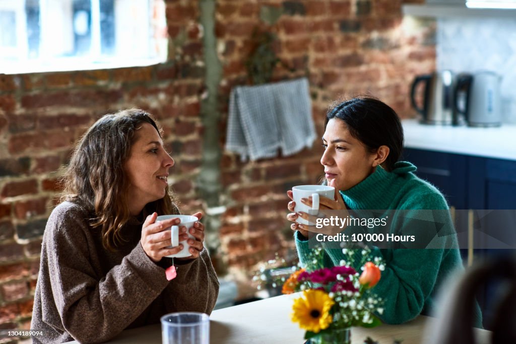 Two women enjoying hot drink having conversation