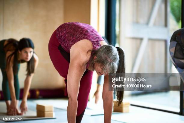 female amputee doing forward bend in yoga studio - older woman bending over stock pictures, royalty-free photos & images