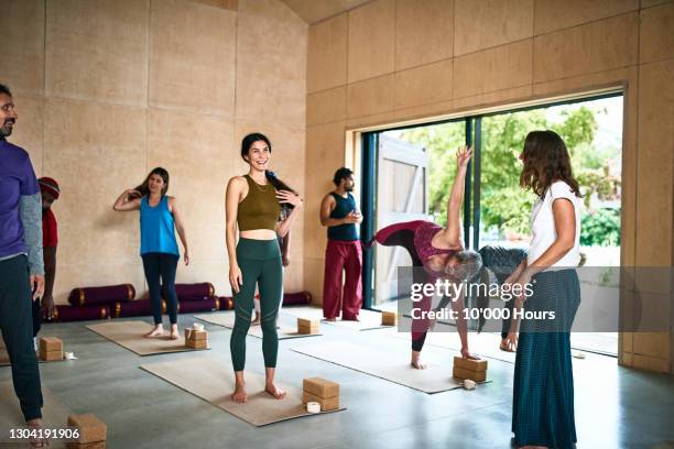 informal yoga studio with teacher talking to student - yoga studio stock pictures, royalty-free photos & images