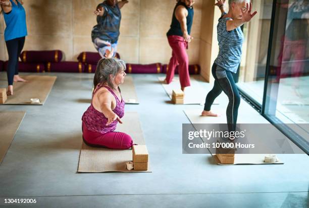 female amputee on yoga mat with arm out - adaptation film stock-fotos und bilder