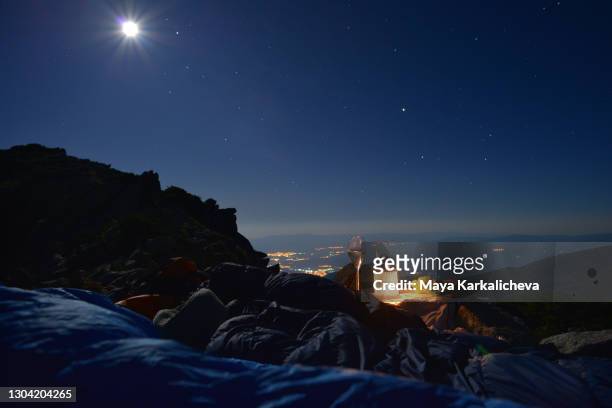 sleeping under the stars, full moon rising behind a mountain range - voyage zen stock-fotos und bilder