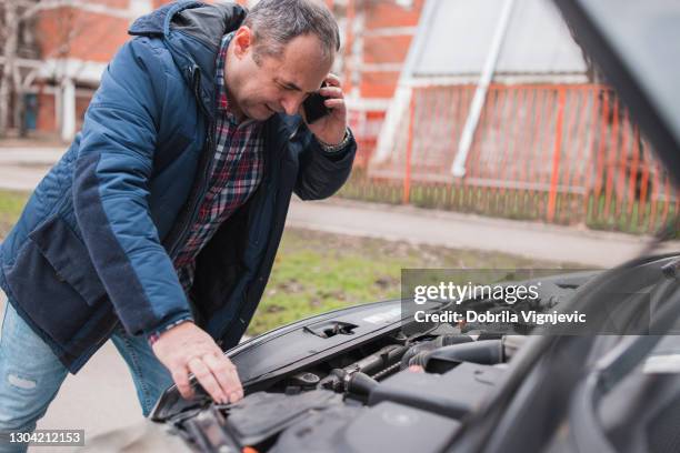 man having phone conversation when looking under car hood - frustrated workman stock pictures, royalty-free photos & images