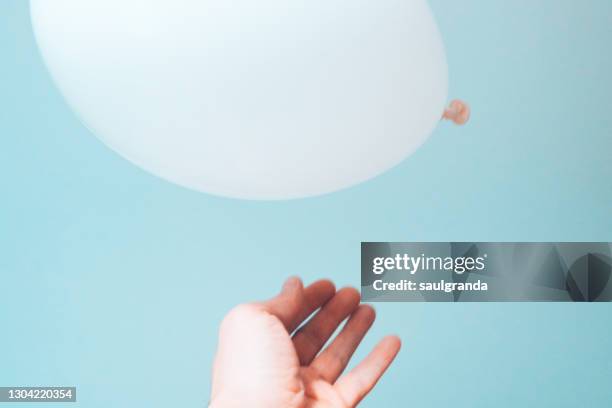 hand releasing a white balloon into the air - releasing fotografías e imágenes de stock