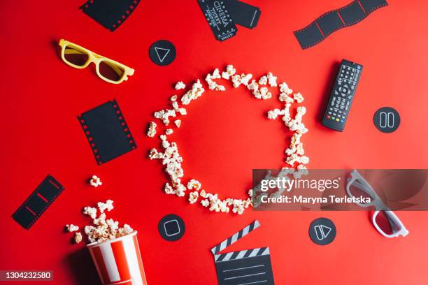 cinema paraphernalia and popcorn on a red background. - movie and tv awards stock pictures, royalty-free photos & images