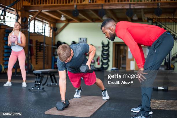 young man exercising with dumbbells - prop sporting position stock pictures, royalty-free photos & images