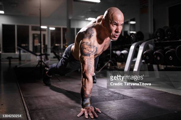 athlete muscular bodybuilder with tattoo in the gym training in plank position - muster stock pictures, royalty-free photos & images