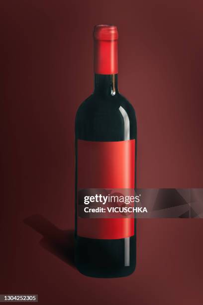 bottle of red wine with blank red label at red background. - ワインボトル ストックフォトと画像