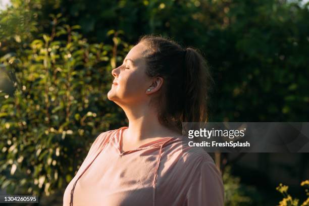 gelukkige te zware vrouw die van het zonnige weer in haar tuin geniet - voluptueus stockfoto's en -beelden