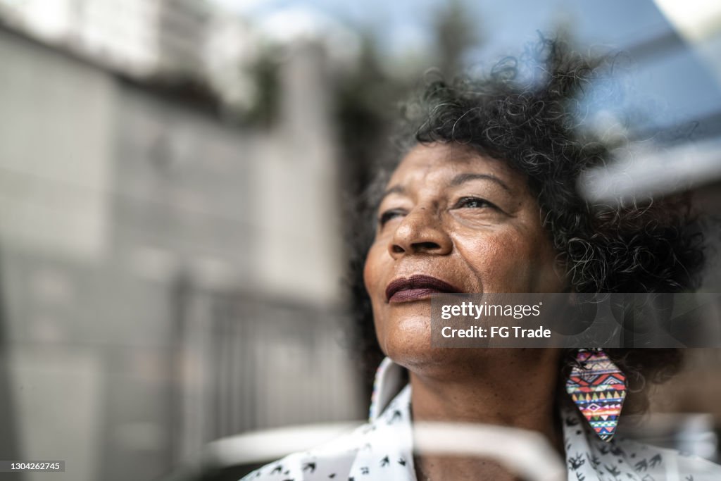 Idosa olhando pela janela em casa