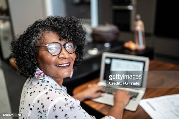 portrait of a senior woman working at home - black woman looking over shoulder stock pictures, royalty-free photos & images