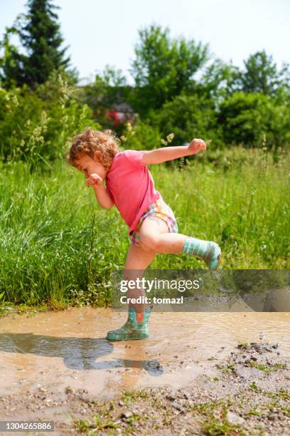 child enjoying a big puddle of mudd - stamping feet stock pictures, royalty-free photos & images