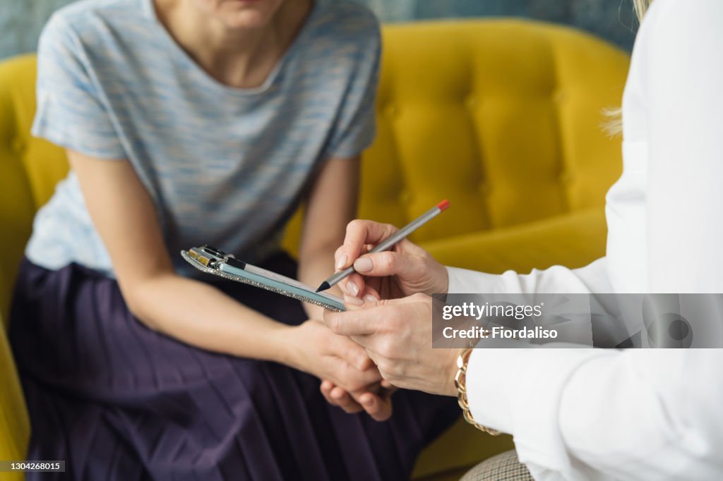 Woman writting to patient girl.