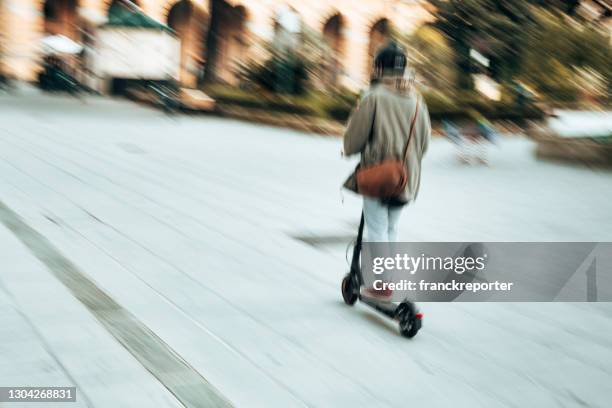 rear view of a woman on the push scooter - woman riding scooter stock pictures, royalty-free photos & images