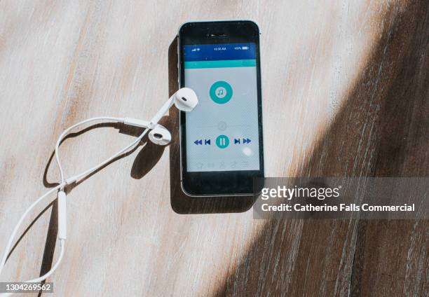 top down image of a mobile phone displaying a music app and earphones - downloading photos et images de collection