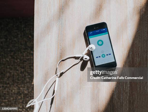 top down image of a mobile phone displaying a music app and earphones - auscultador equipamento áudio imagens e fotografias de stock