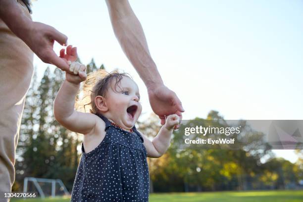 a baby looking straight ahead with a big smile while learning how to walk. - family smile photos et images de collection