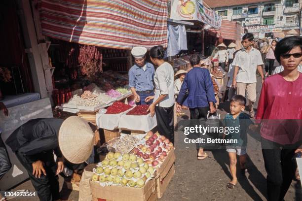 Shoppers at a fruit stall during the pre-Tet shopping rush, the Tet celebration being important to Vietnamese culture, in the central market of...