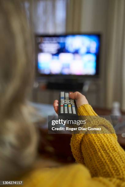 hands of a young woman watching tv with remote control - vertical tv stock pictures, royalty-free photos & images