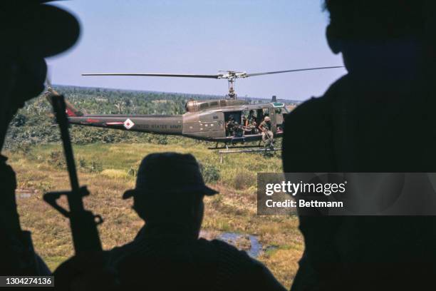 Silhouettes of soldiers of the United States Army 9th Infantry Division 3 Battalion looking out at a Bell UH-1 Iroquois helicopter, with soldiers...