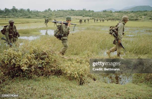 Soldiers of the United States Army's 1st Cavalry Division, each carrying their M16A1, through a paddy field, during a search-and-destroy mission in...