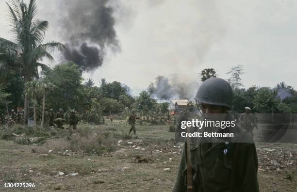 Officers of the Cambodian Army searching for Viet Cong forces, as smoke rises beyond the trees in the background, in Sa Ang, Cambodia, 24th April...