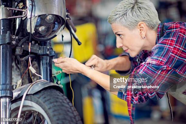portrait of woman working in custom motorcycle garage - motorcycle one wheel imagens e fotografias de stock