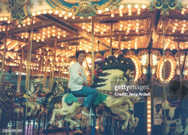 fed up mother, bored mother: unamused woman on carousel during boring vacation - draaimolen stockfoto's en -beelden