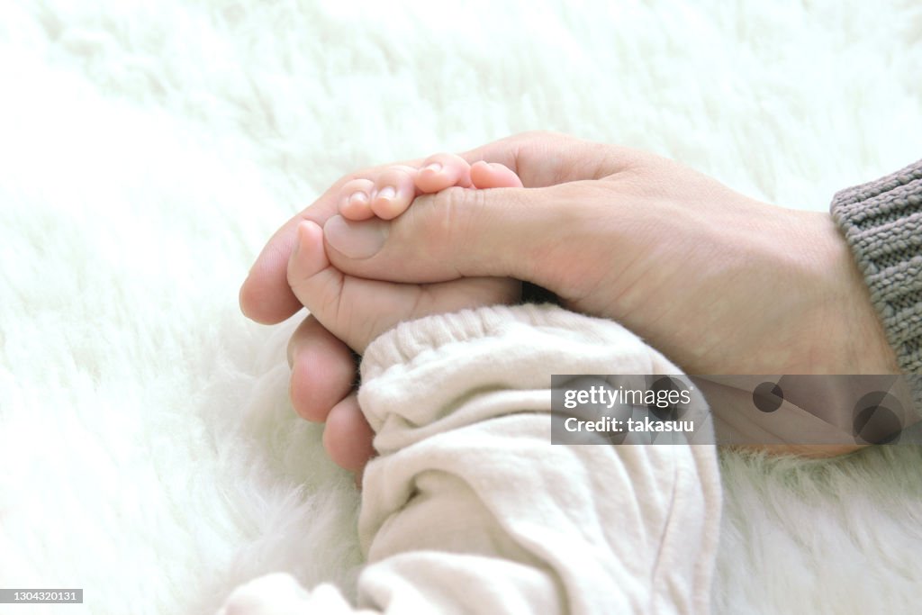 Baby and mother's hand on soft carpet