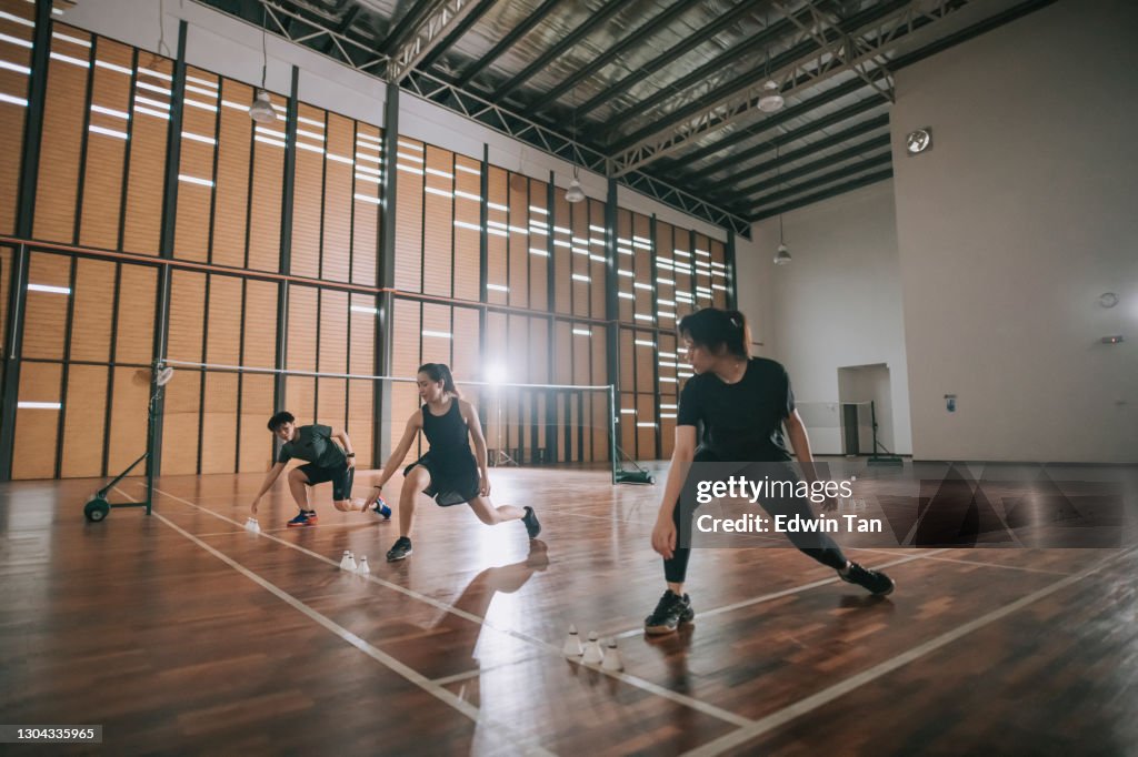 Low angle asian chinese badminton players practicing in badminton court warm up exercise before practicing