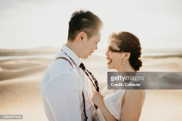 asian bride and groom, desert elopement, holding hands, smiling, rear view - destination wedding imagens e fotografias de stock
