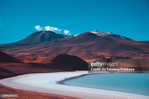 red volcanic mountains and a blue salt lake. beautiful nature background - landschaft stock-fotos und bilder