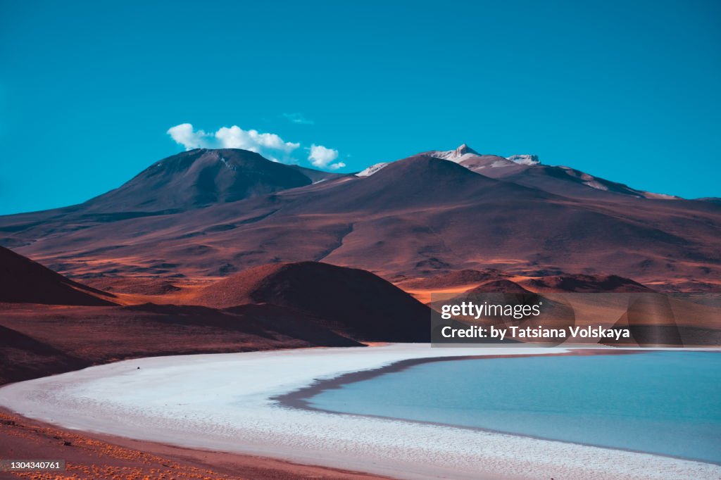Red volcanic mountains and a blue salt lake. Beautiful nature background