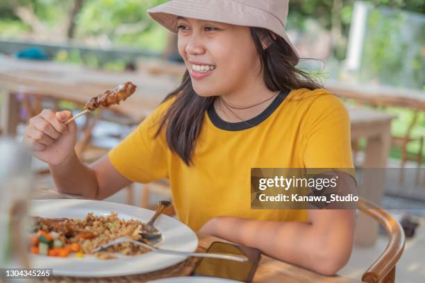 young indonesian woman eating chicken satay and fried rice - eating spicy food stock pictures, royalty-free photos & images