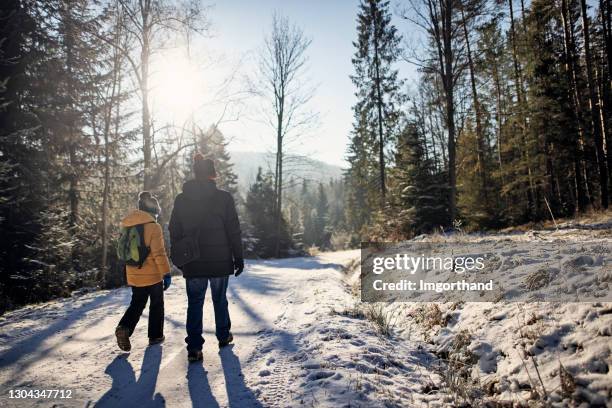 grandfather and grandson enjoy hiking in beautiful winter forest - grandfather child snow winter stock pictures, royalty-free photos & images