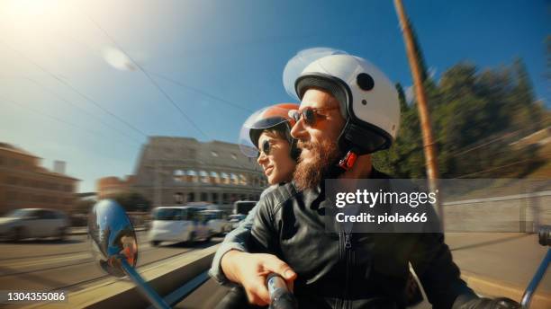 selfie scooter riding: tourist couple on the motorbike by the coliseum of rome - couple scooter stock pictures, royalty-free photos & images