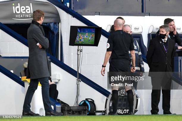 Referee Lee Mason looks at the pitch side VAR monitor before awarding Brighton and Hove Albion a penalty due to a hand ball during the Premier League...