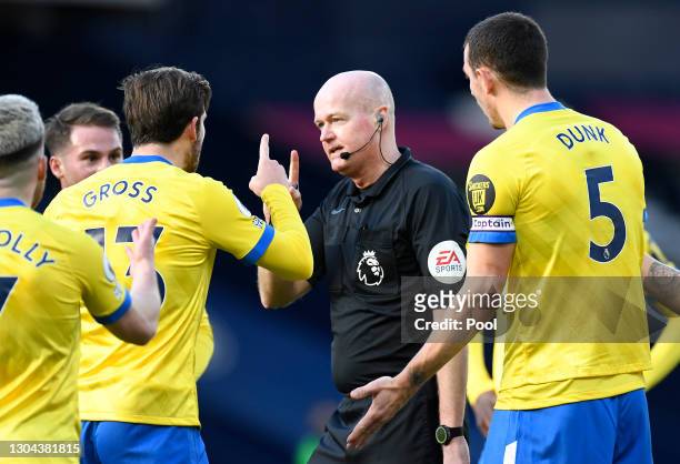 Aaron Connolly, Pascal Gross and Lewis Dunk of Brighton and Hove Albion confront referee Lee Mason as he makes changes to his decision to disallow,...