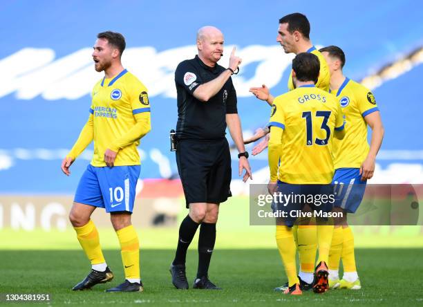 Lewis Dunk and Pascal Gross of Brighton and Hove Albion confront referee Lee Mason as he makes changes to his decision to disallow, then allow, then...