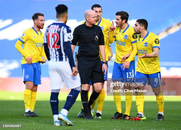 Lewis Dunk, Pascal Gross and Neal Maupay of Brighton and Hove Albion confront referee Lee Mason as he makes changes to his decision to disallow, then...