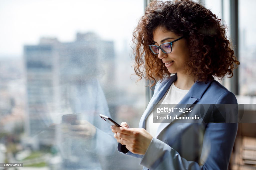 Jovem empresária usando telefone inteligente no escritório