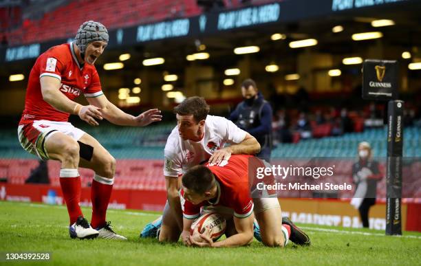 Josh Adams of Wales beats George Ford of England to score their side's first try as Jonathan Davies celebrates during the Guinness Six Nations match...