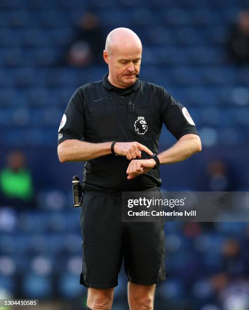 Referee Lee Mason checks his watch during the Premier League match between West Bromwich Albion and Brighton & Hove Albion at The Hawthorns on...