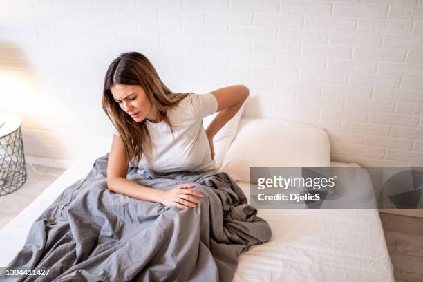 mujer en la cama con dolor de espalda. - back pain fotografías e imágenes de stock