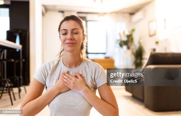 young woman meditating at home. - healthy heart stock pictures, royalty-free photos & images